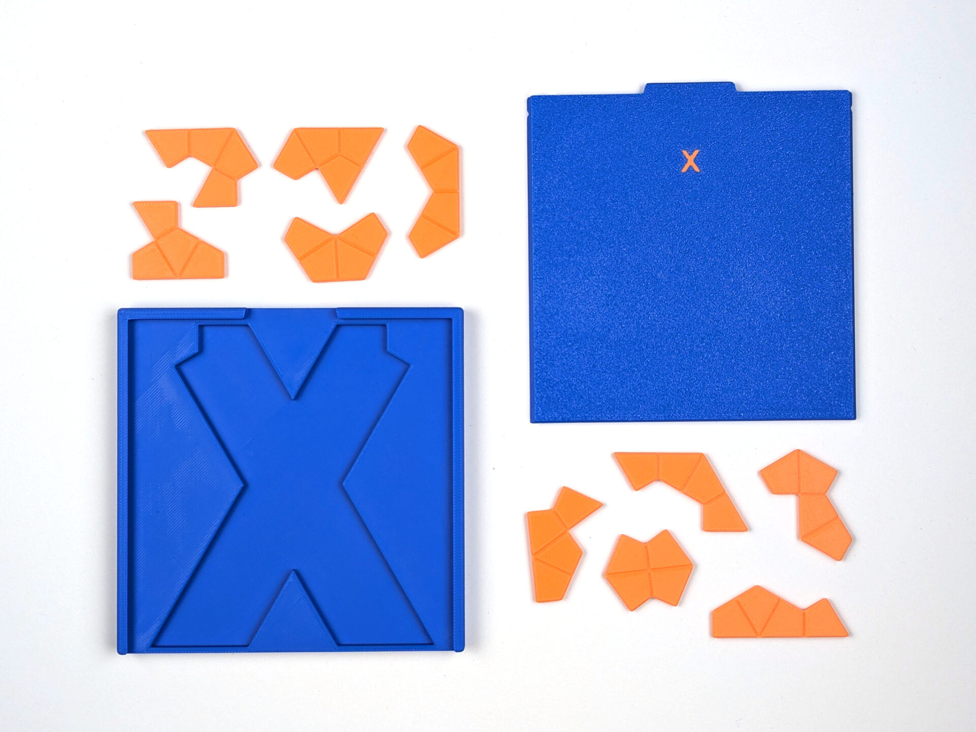 Zehn orangefarbene Waben-Tetrakites neben der leeren X-Puzzlebox und ihrem blauen Schiebedeckel